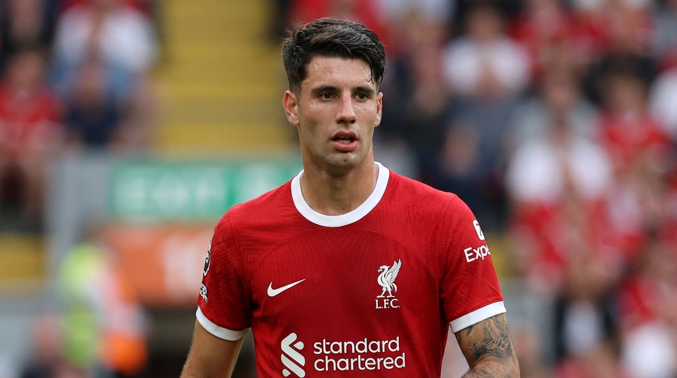 Dominik Szoboszlai wearing a red Liverpool kit looking focused on the pitch with a blurred stadium background